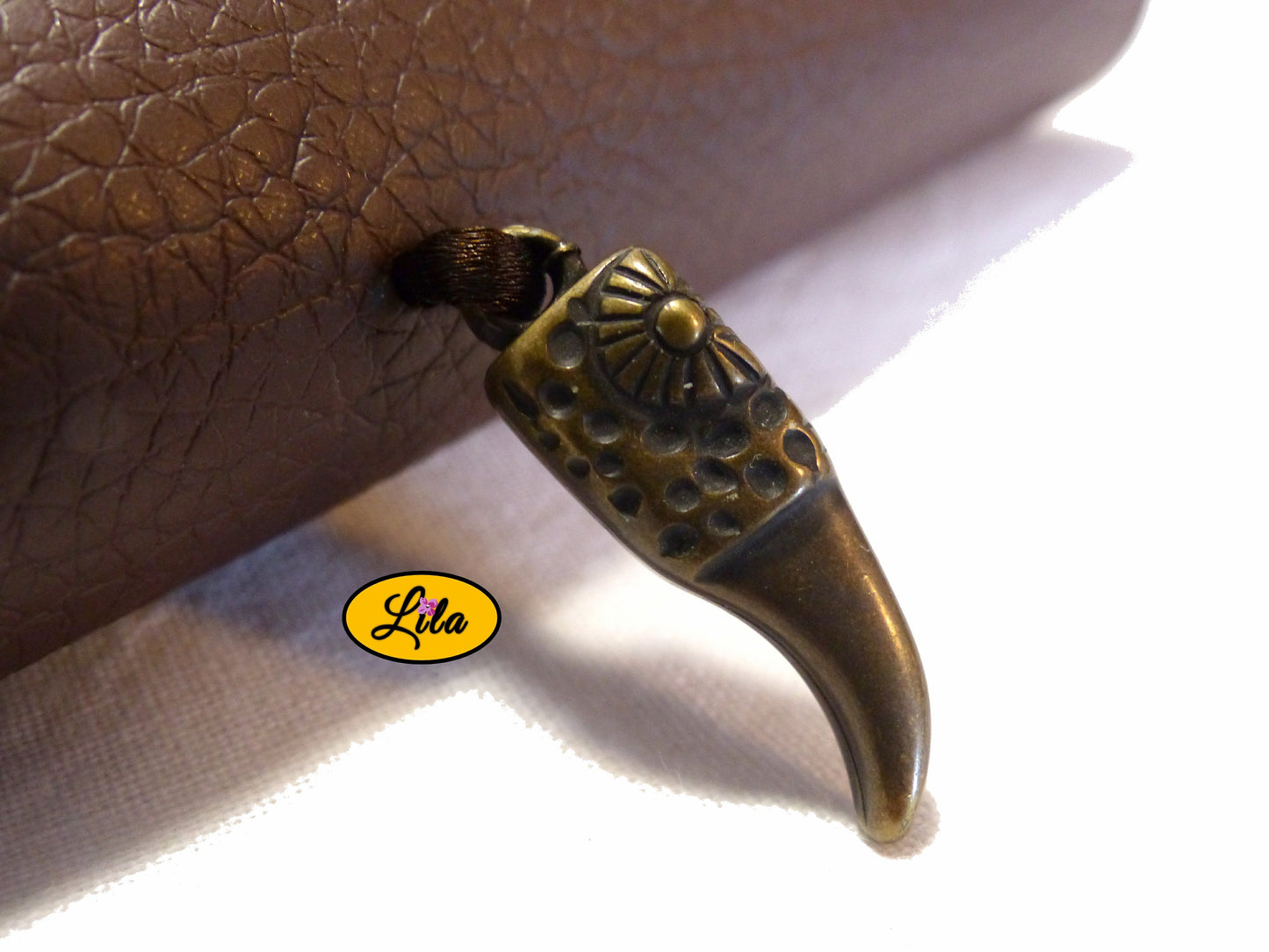 Zoom sur le pendentif en plastique dur représentant une corne couleur bronze décorant l’étui à lunettes en simili brun détail original et bohème