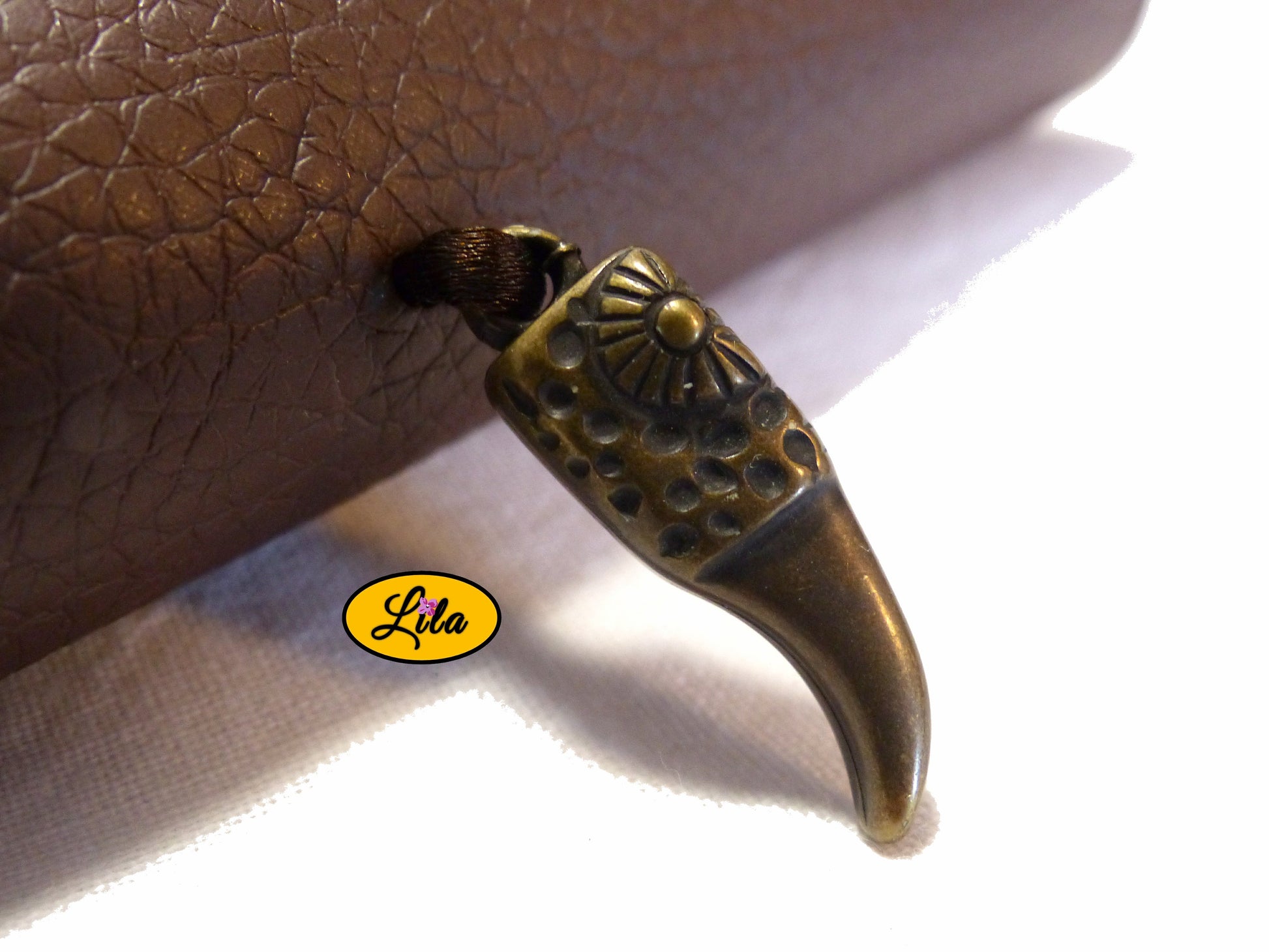 Zoom sur le pendentif en plastique dur représentant une corne couleur bronze décorant l’étui à lunettes en simili brun détail original et bohème