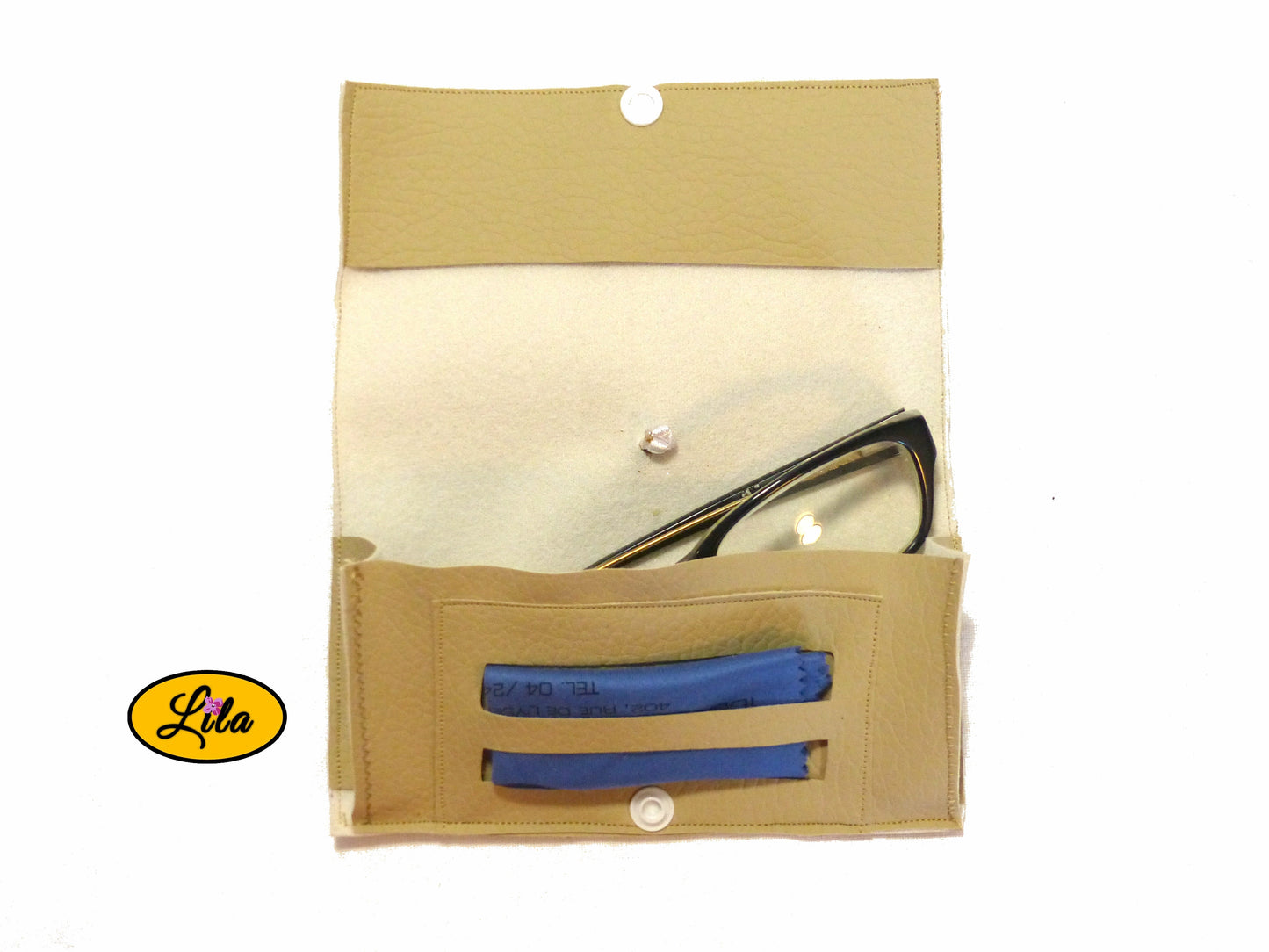 Étui à lunettes en simili crème ouvert à plat avec paire de lunettes et lingettes rangées dans le compartiment intérieur sur fond blanc style artisanal et fonctionnel
