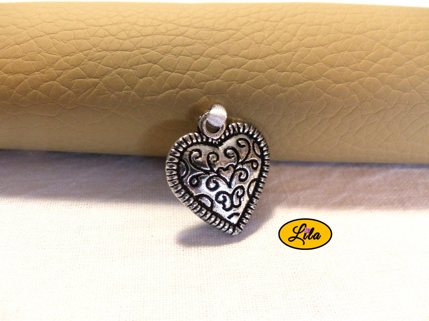 Zoom sur le pendentif cœur décoratif avec motif noir de l’étui à lunettes en simili crème détail féminin et vintage