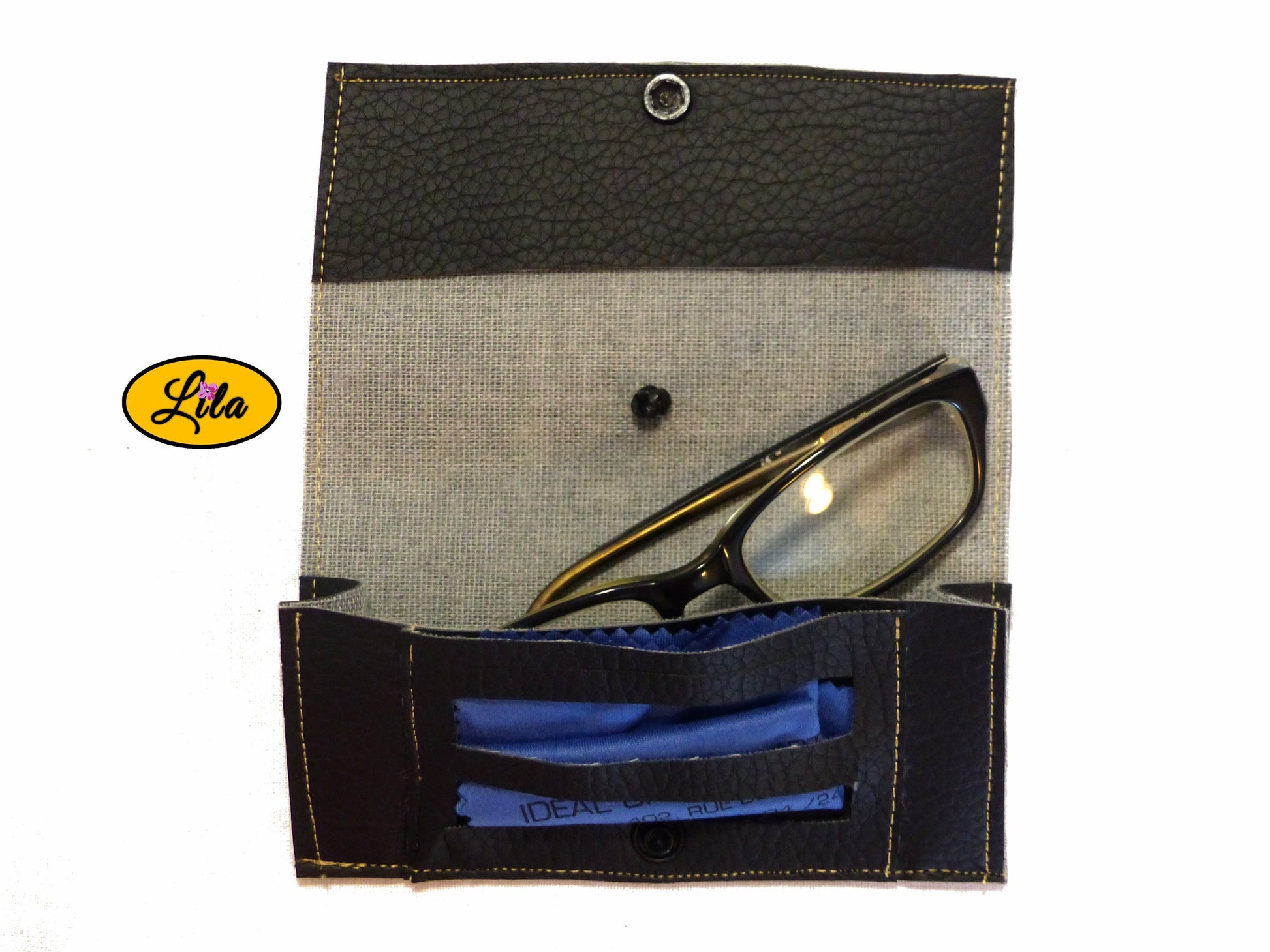 Étui à lunettes en simili noir ouvert à plat avec paire de lunettes et lingettes rangées dans le compartiment intérieur sur fond blanc style chic et fonctionnel