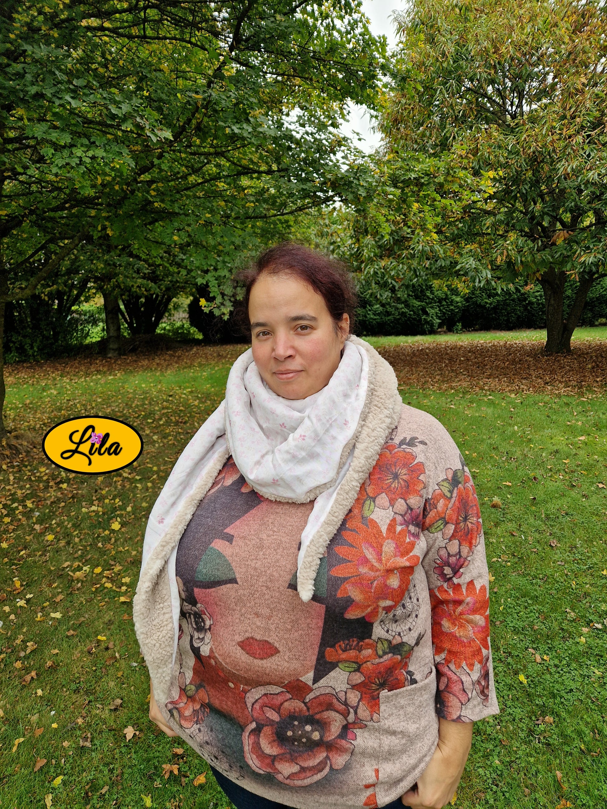 Foulard triangulaire en coton blanc à motifs roses porté par une jeune femme dans les bois en automne photo cadrée jusqu’à la taille avec mains dans les poches style cocooning et naturel