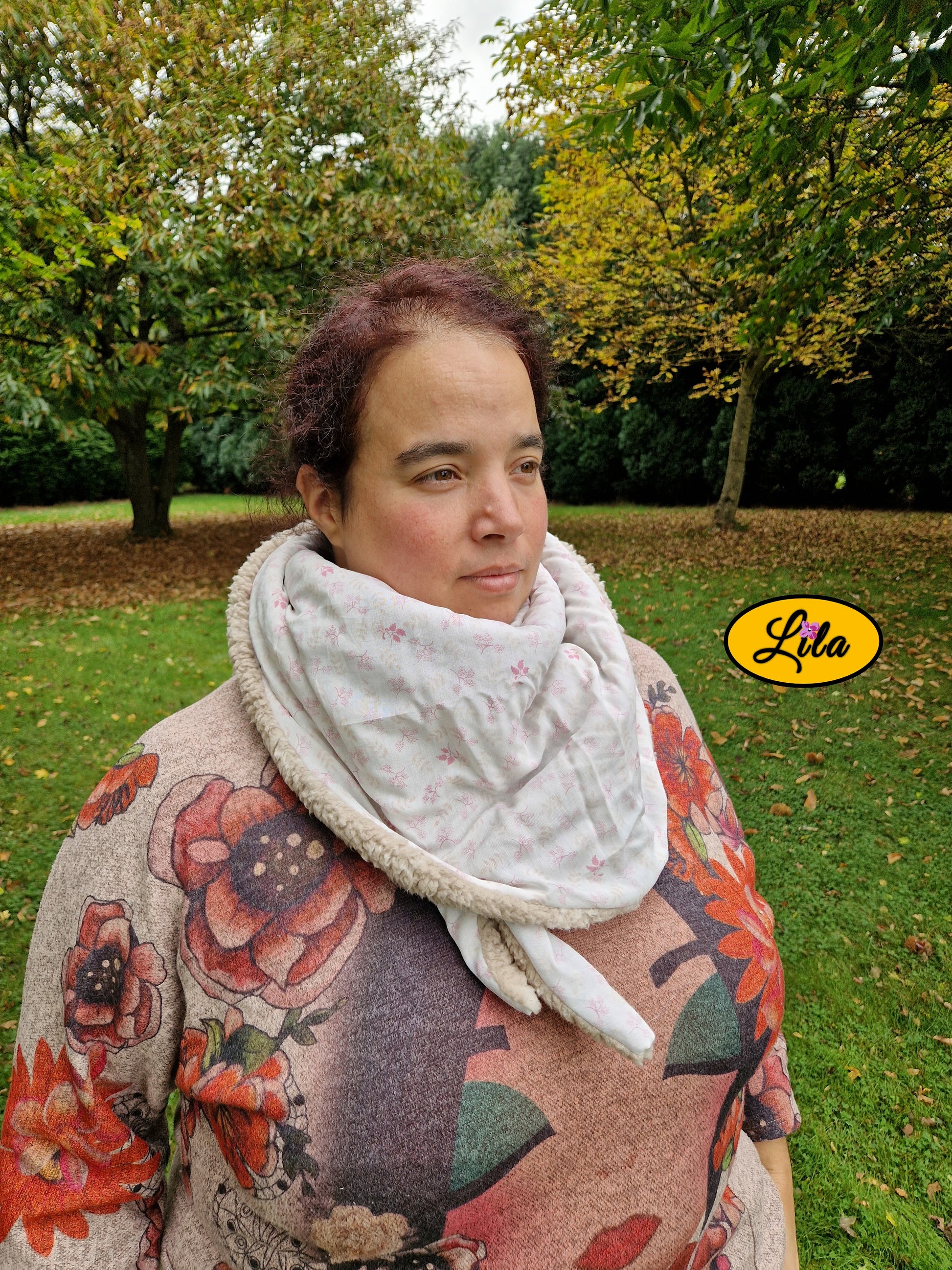 Foulard triangulaire en coton blanc à motifs roses porté fermé par une jeune femme de profil regard tourné vers la droite avec nœud caché sous la pointe du foulard style automnal et élégant