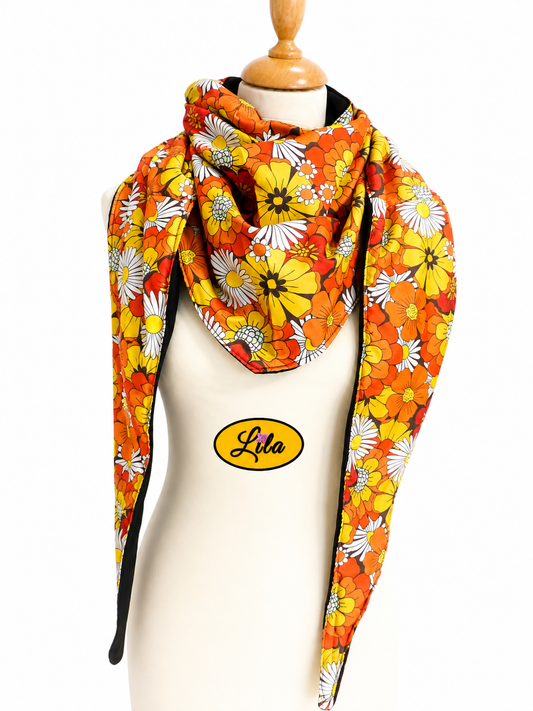Foulard triangulaire en tissu fleuri orange vintage avec doublure polaire noire porté sur mannequin de couture sur fond blanc style rétro et hivernal