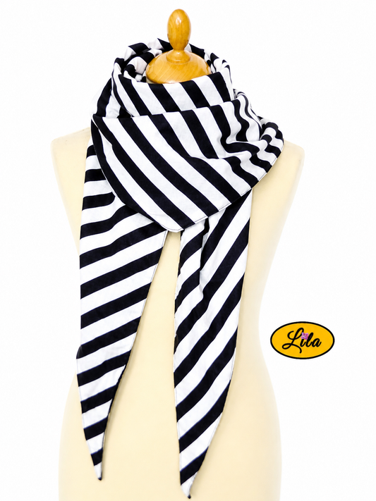 Foulard triangulaire à lignes noir et blanc avec doublure polaire noire porté sur mannequin de couture sur fond blanc style graphique et hivernal