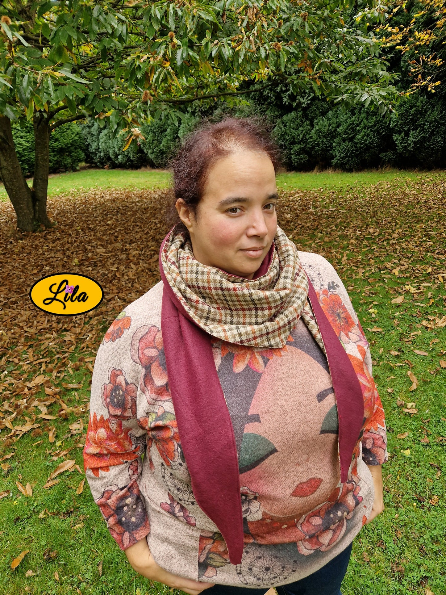 Foulard triangulaire rétro en tweed brun avec doublure polaire bordeaux porté par une jeune femme dans un jardin en automne vue légèrement de haut style vintage et cocooning