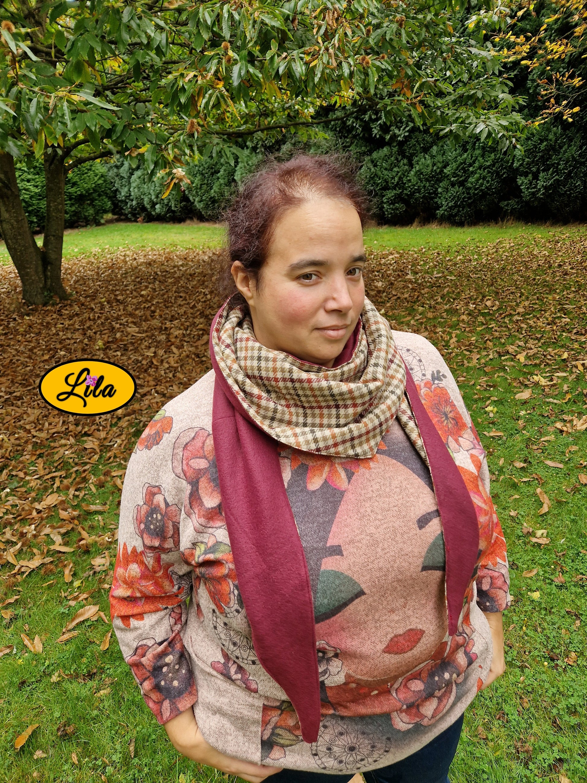 Foulard triangulaire rétro en tweed brun avec doublure polaire bordeaux porté par une jeune femme dans un jardin en automne vue légèrement de haut style vintage et cocooning