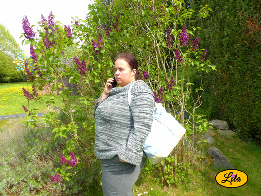 Grand sac en jeans clair recyclé et simili cuir crème porté par une femme au téléphone devant un étang mettant en valeur le porté du sac dans une scène du quotidien