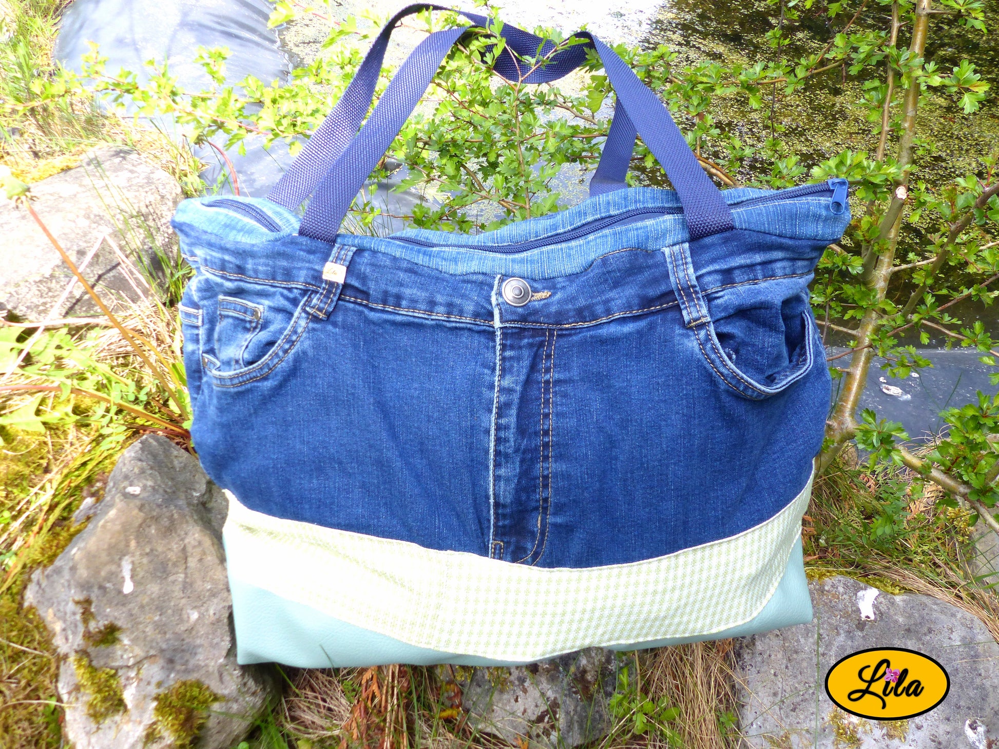 Grand sac en jeans recyclé et simili cuir vert menthe posé sur une pierre au bord d'un étang dans un décor naturel mettant en valeur son style écoresponsable