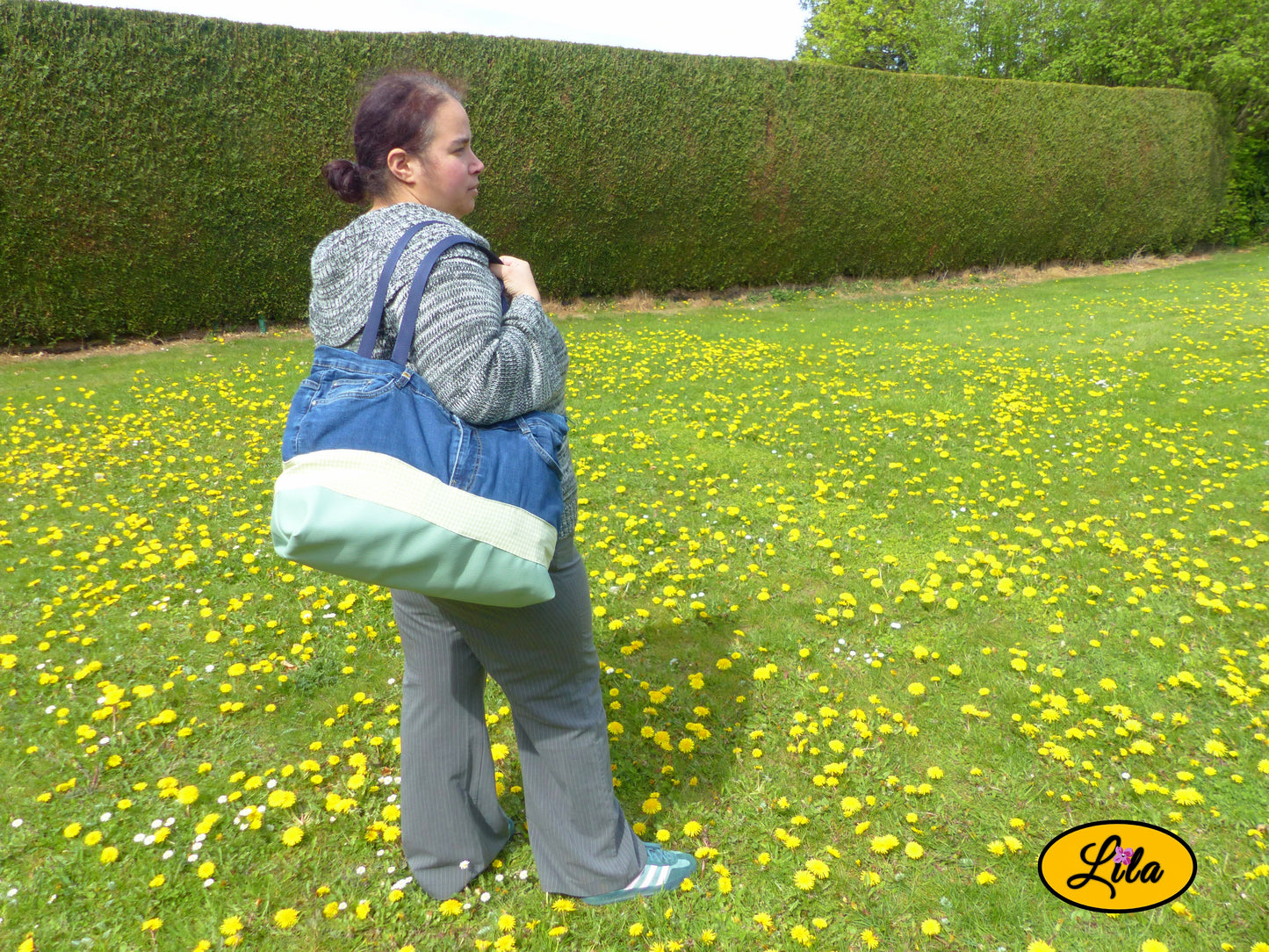Grand sac en jeans recyclé et simili cuir vert menthe porté par une jeune femme de dos dans un jardin mettant en valeur le porté du sac en situation réelle