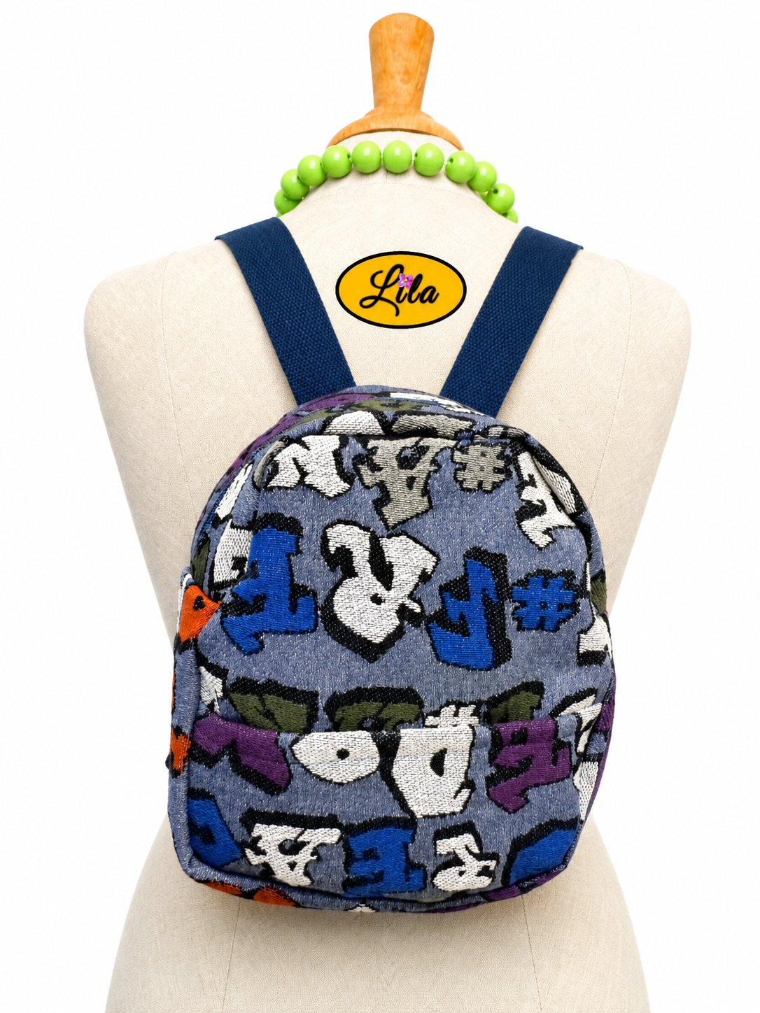 Mini sac à dos bleu avec écriture, poche avant et sangle bleue porté sur mannequin de couture sur fond blanc style urbain et moderne