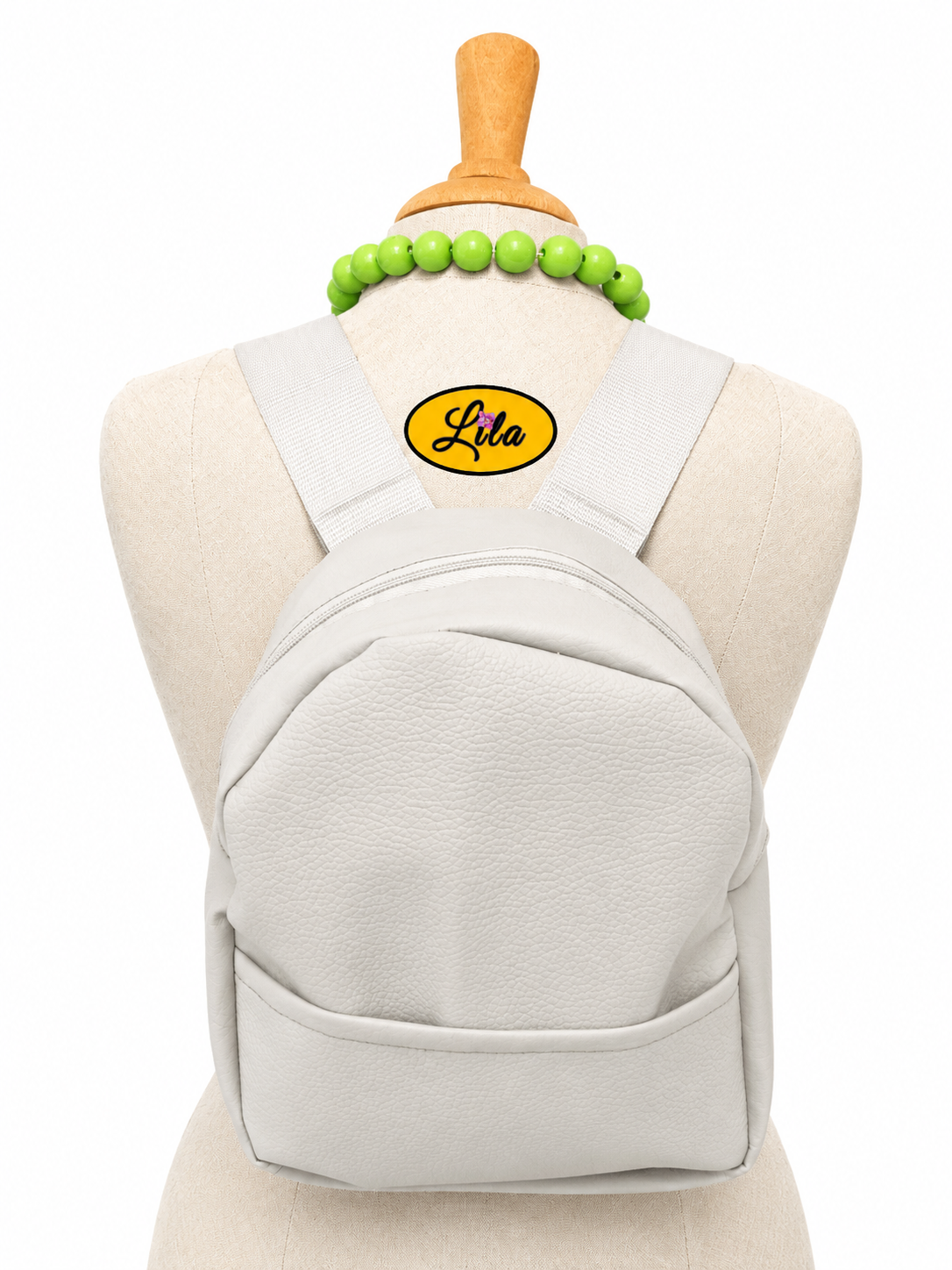 Mini sac à dos en simili gris clair avec poche avant et sangle blanche porté sur mannequin de couture sur fond blanc style moderne et élégant