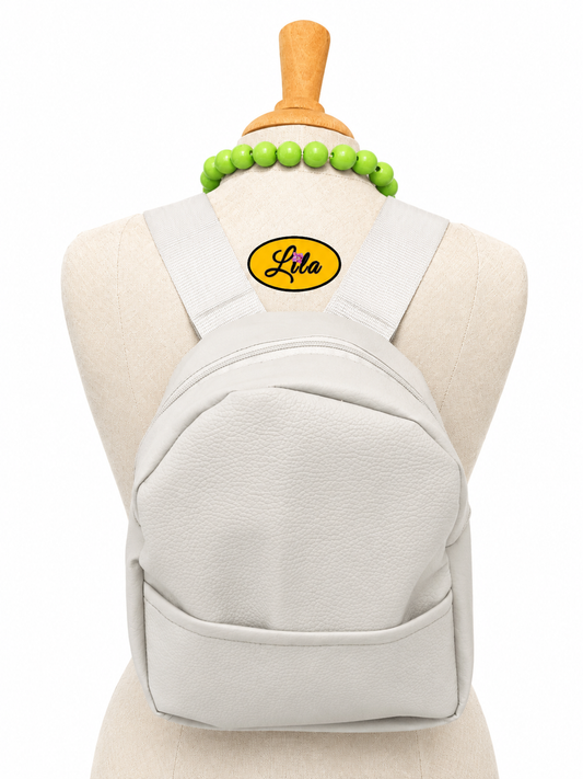 Mini sac à dos en simili gris clair avec poche avant et sangle blanche porté sur mannequin de couture sur fond blanc style moderne et élégant