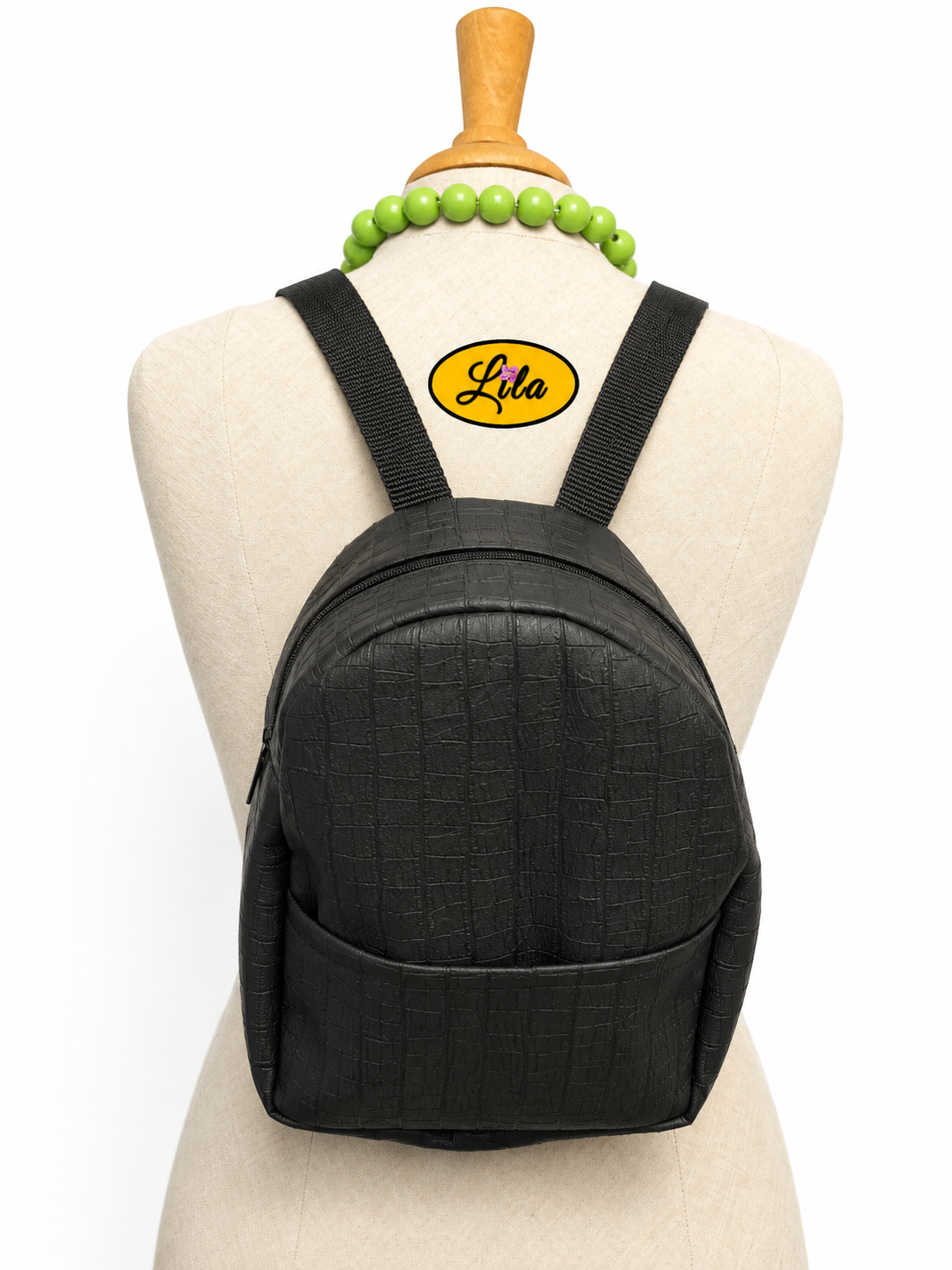 Mini sac à dos en simili noir craquelé avec poche avant et fines brides noires porté sur mannequin de couture sur fond blanc style moderne et rock chic