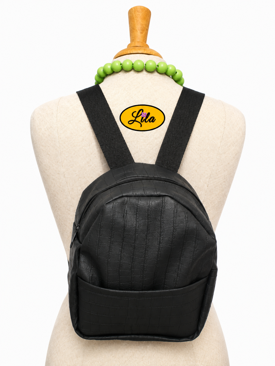 Mini sac à dos en simili noir craquelé avec poche avant et sangles noires porté sur mannequin de couture sur fond blanc style urbain et tendance