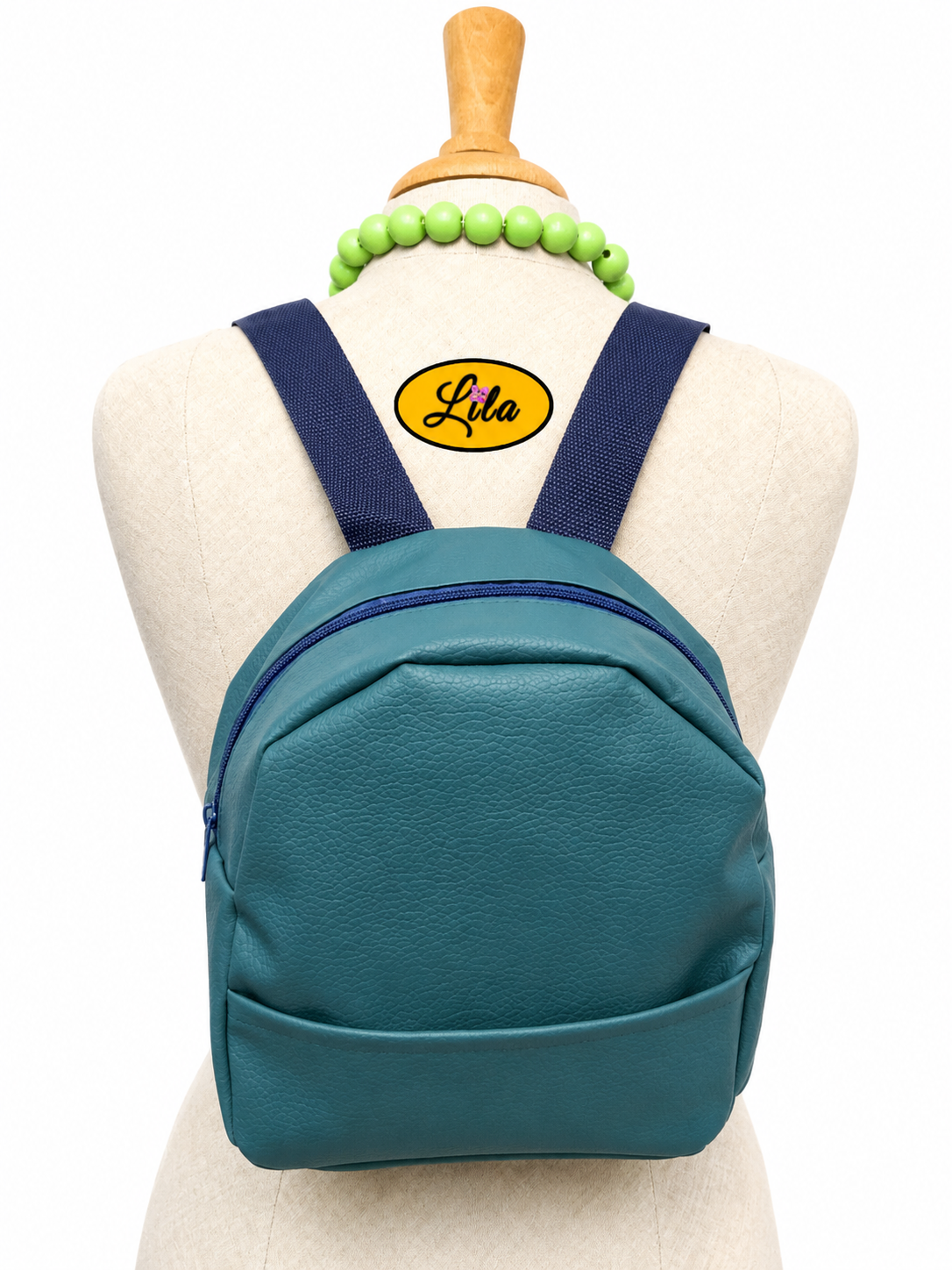 Mini sac à dos turquoise avec poche avant et sangle bleue porté sur mannequin de couture sur fond blanc style moderne et tendance