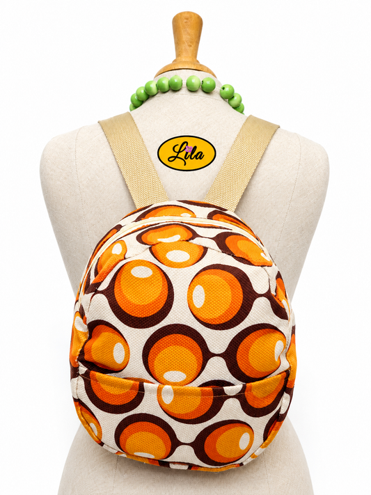 Mini sac à dos en tissu vintage à ronds orange avec poche avant et sangle sable porté sur mannequin de couture sur fond blanc style rétro et tendance