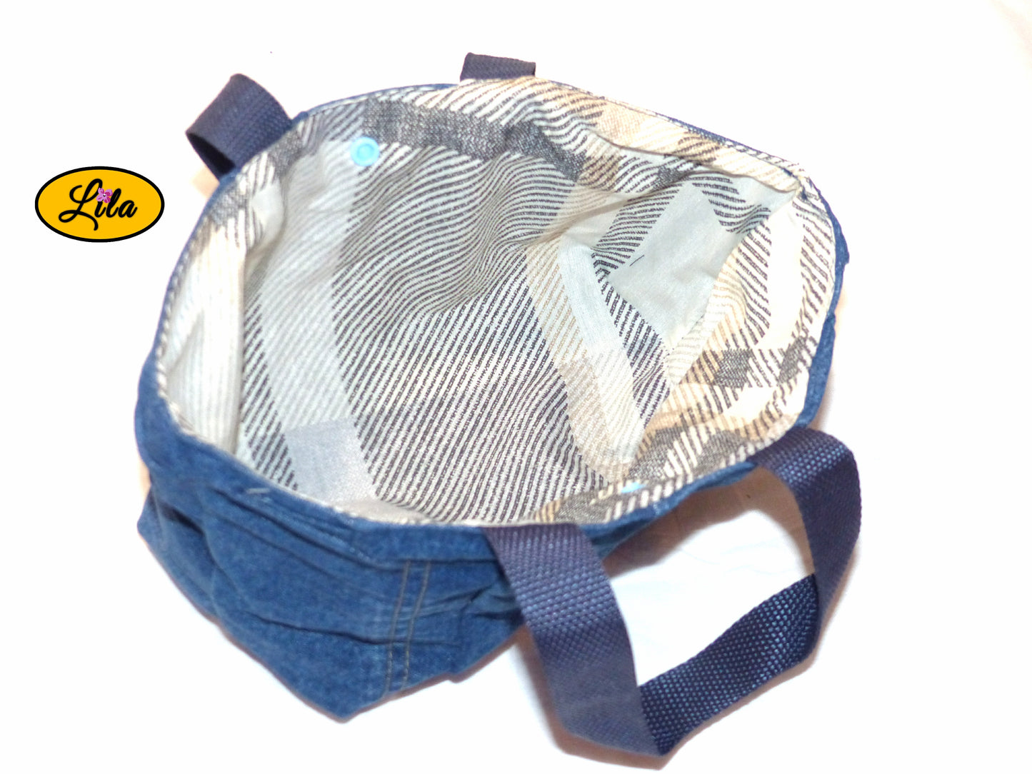 Vue de haut du mini sac à main en jeans recyclé ouvert avec doublure visible et attache pression bleue sur fond blanc