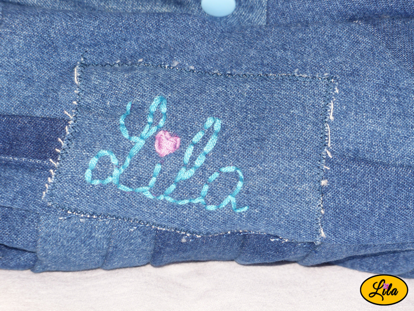 Zoom sur la broderie Lila en fil bleu avec cœur rose sur mini sac à main en jeans recyclé détail artisanal et personnalisé