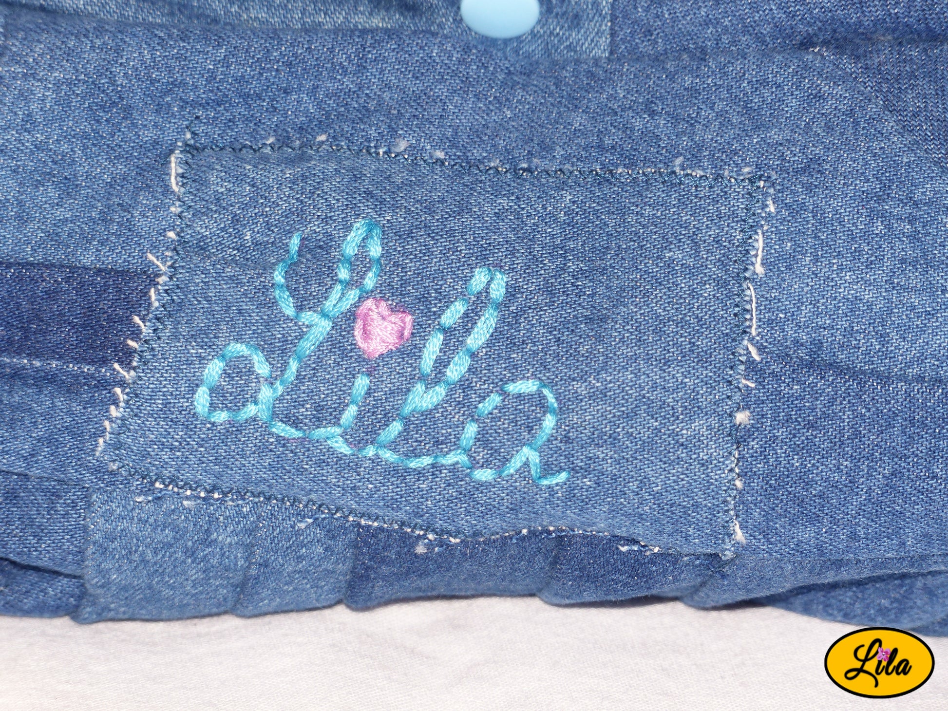 Zoom sur la broderie Lila en fil bleu avec cœur rose sur mini sac à main en jeans recyclé détail artisanal et personnalisé