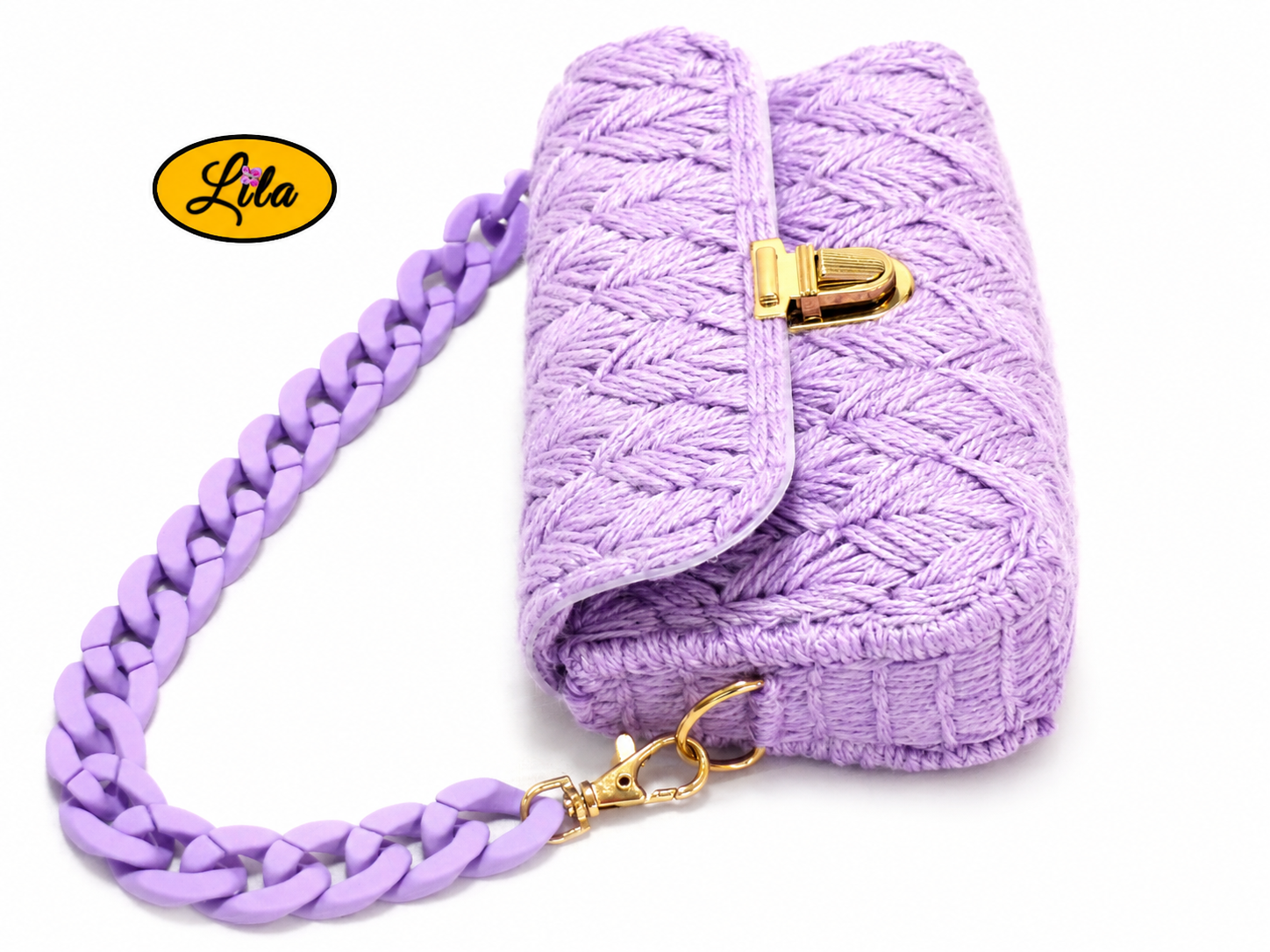 Petit sac à main aux brins lilas sur canevas rigide couché sur fond blanc avec chaîne lilas en grosse maille posée sur le dessus du sac
