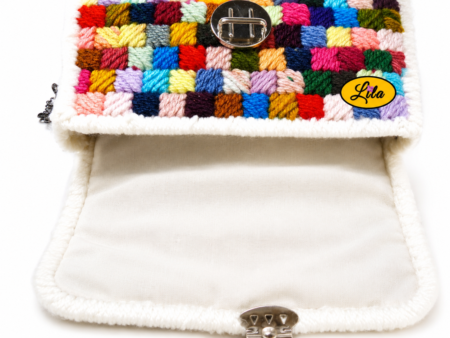 Petit sac à main à carrés multicolores en laine sur canevas rigide ouvert sur fond blanc avec doublure blanche et fermeture du sac visible