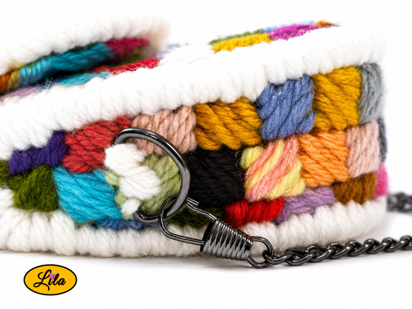 Zoom sur le côté supérieur du petit sac à main multicolore couché sur fond blanc avec anneau métallique noir et attache de la chaîne