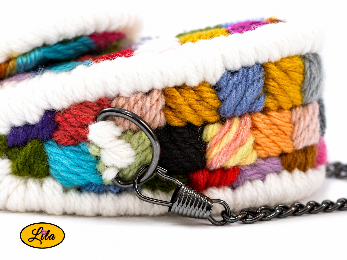 Zoom sur le côté supérieur du petit sac à main multicolore couché sur fond blanc avec anneau métallique noir et attache de la chaîne