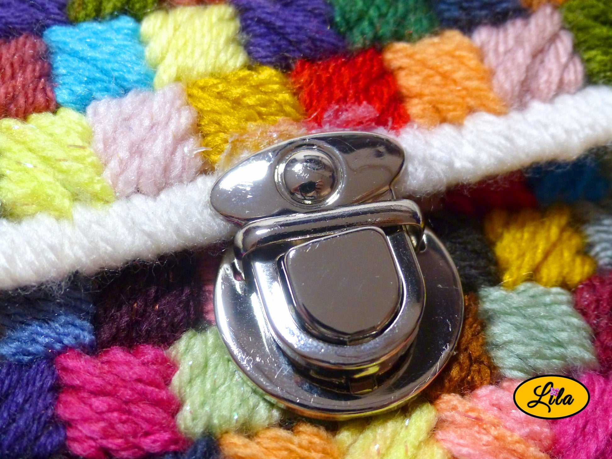 Zoom sur la fermeture cartable argentée du petit sac à main multicolore sur canevas rigide détail finition et attache métallique