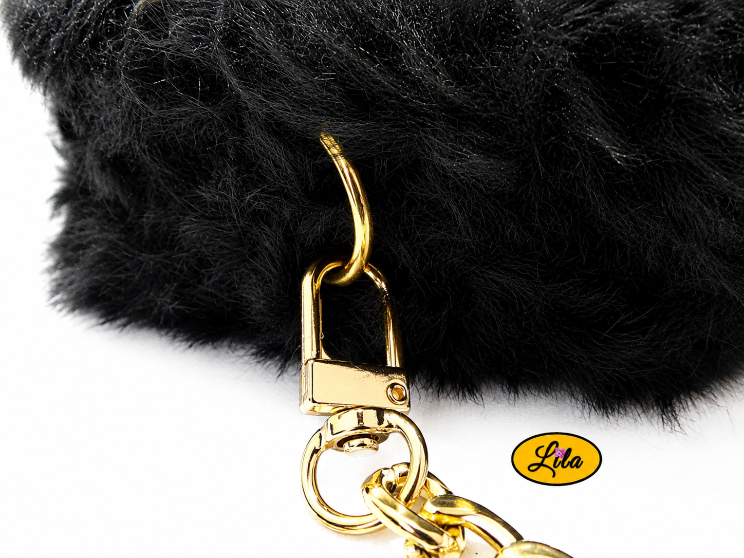 Zoom sur le côté du petit sac à main effet fausse fourrure noire avec anneau doré et attache de la chaîne métallique