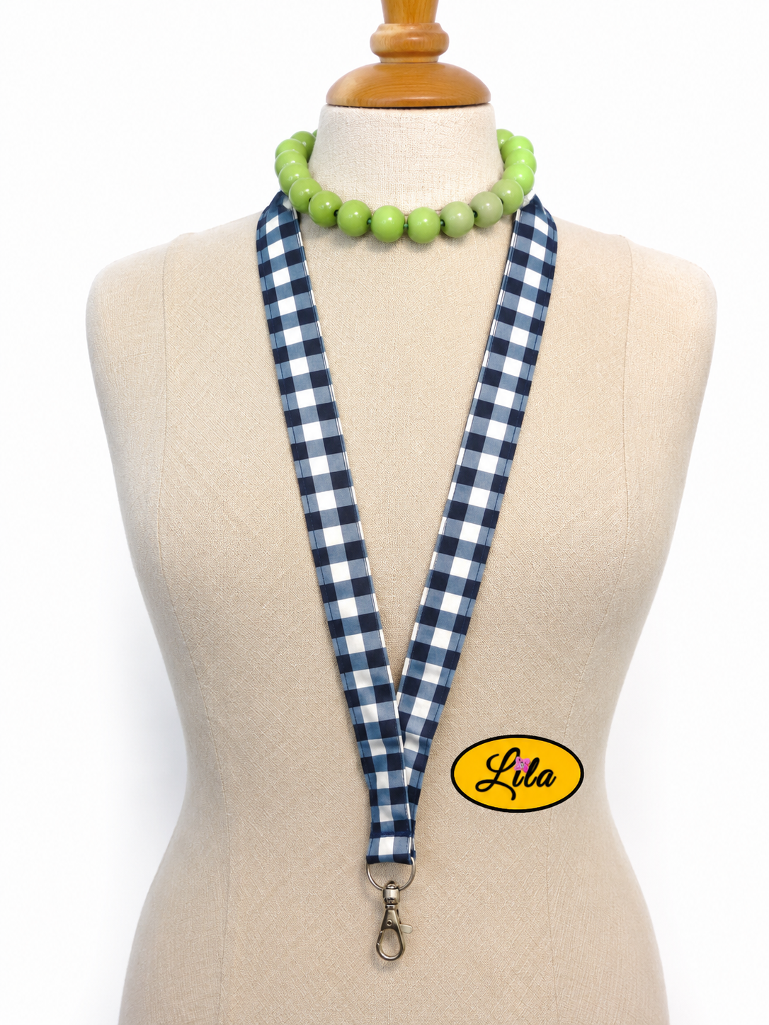 Porte-badge en tissu bleu marine à carreaux blancs porté sur mannequin de couture sur fond blanc avec mousqueton style classique et artisanal
