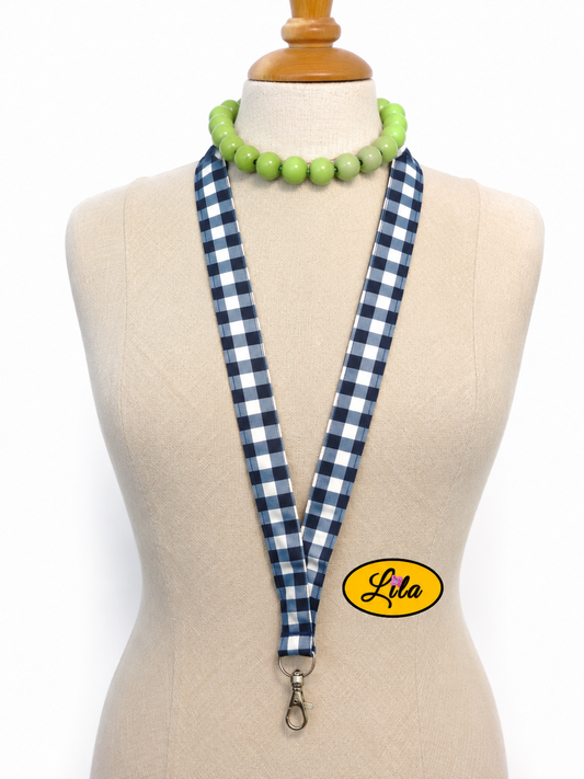 Porte-badge en tissu bleu marine à carreaux blancs porté sur mannequin de couture sur fond blanc avec mousqueton style classique et artisanal