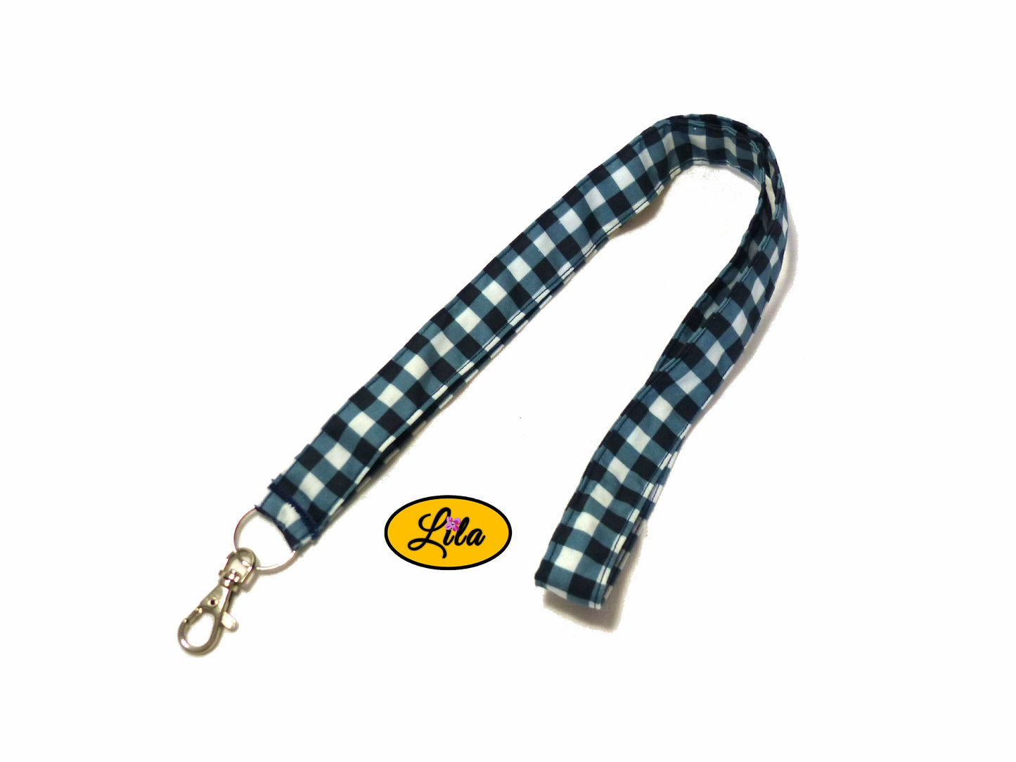Porte-badge en tissu bleu marine à carreaux blancs légèrement replié en deux sur fond blanc avec mousqueton métallique style pratique et rétro