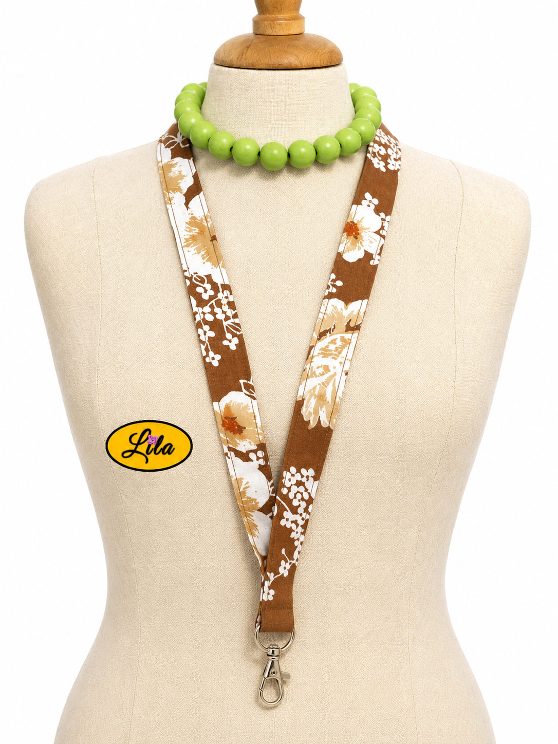 Porte-badge en tissu brun à petites fleurs blanches porté sur mannequin de couture sur fond blanc avec mousqueton style bohème et vintage