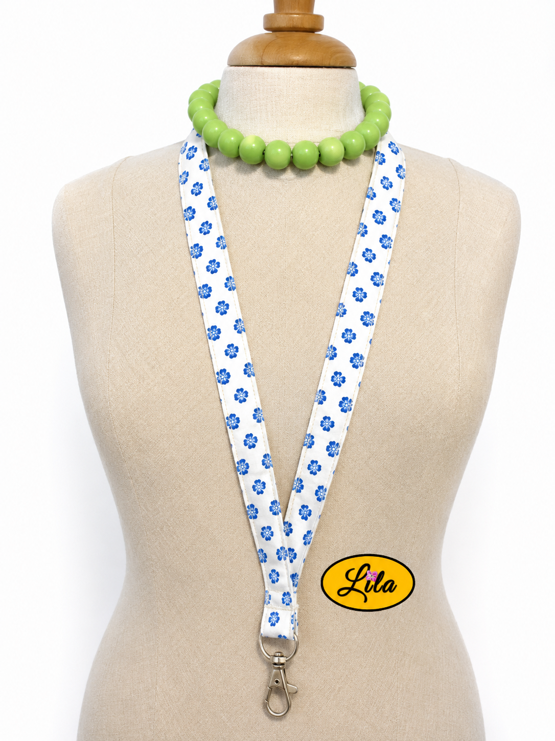 Porte-badge en tissu blanc à petites fleurs bleues porté sur mannequin de couture sur fond blanc avec mousqueton style romantique et artisanal