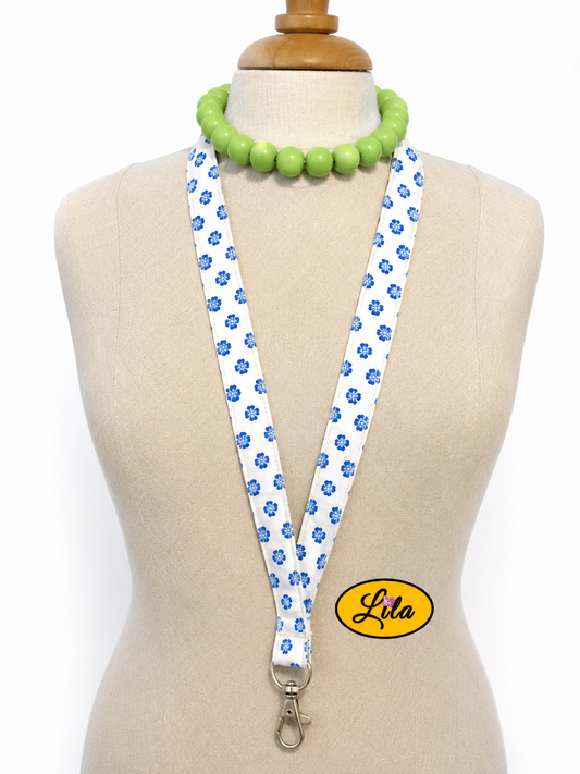 Porte-badge en tissu blanc à petites fleurs bleues porté sur mannequin de couture sur fond blanc avec mousqueton style romantique et artisanal