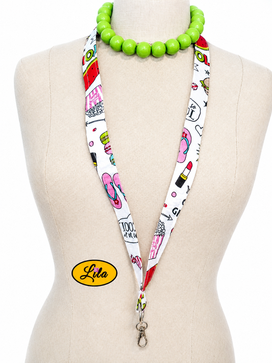 Porte-badge en tissu blanc à motifs girly avec appareils photo maquillage et accessoires féminins porté sur mannequin de couture sur fond blanc avec mousqueton style tendance et artisanal