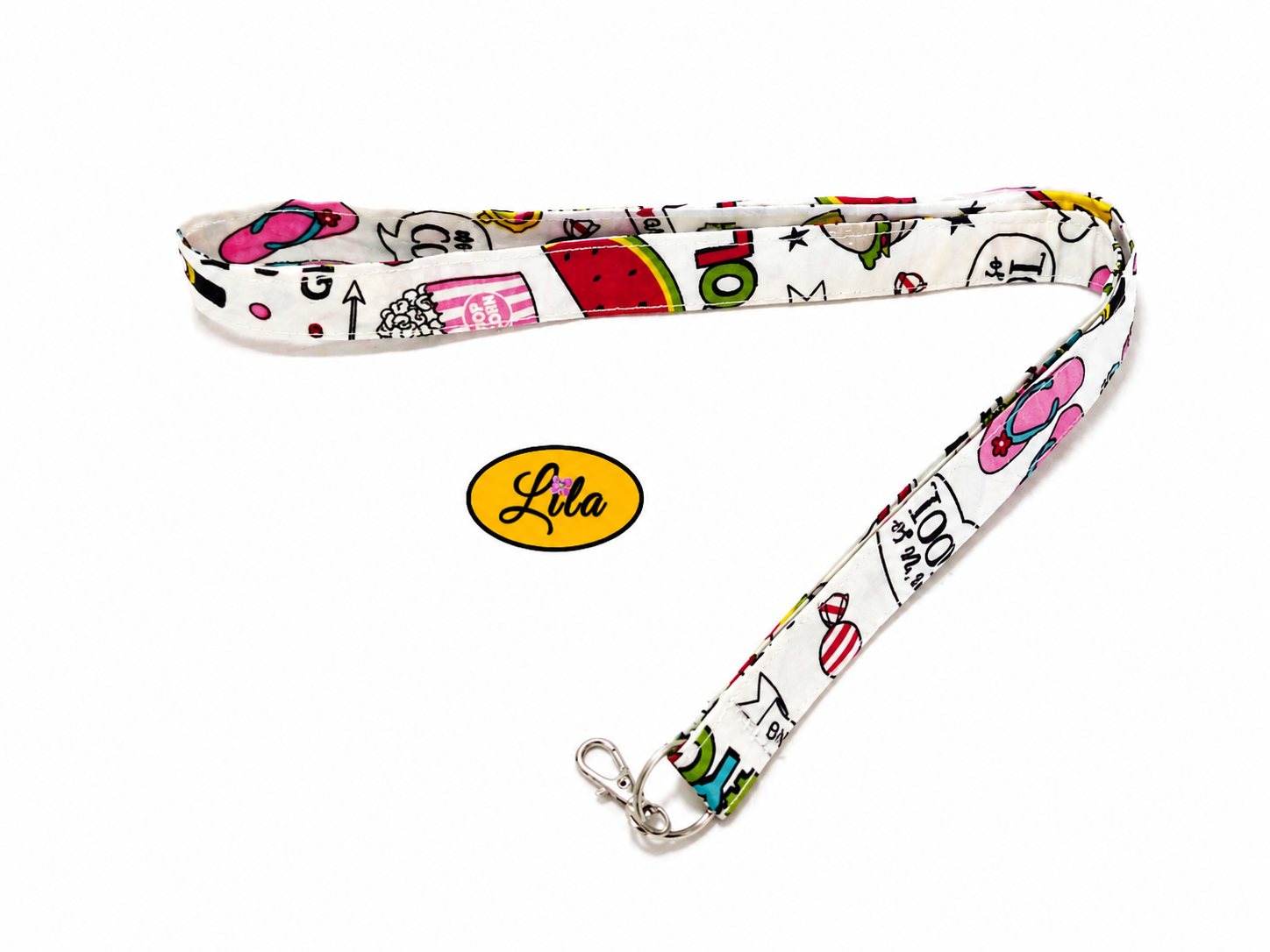 Porte-badge en tissu blanc à motifs girly maquillage et appareils photo légèrement replié en deux sur fond blanc avec mousqueton métallique style féminin et pratique