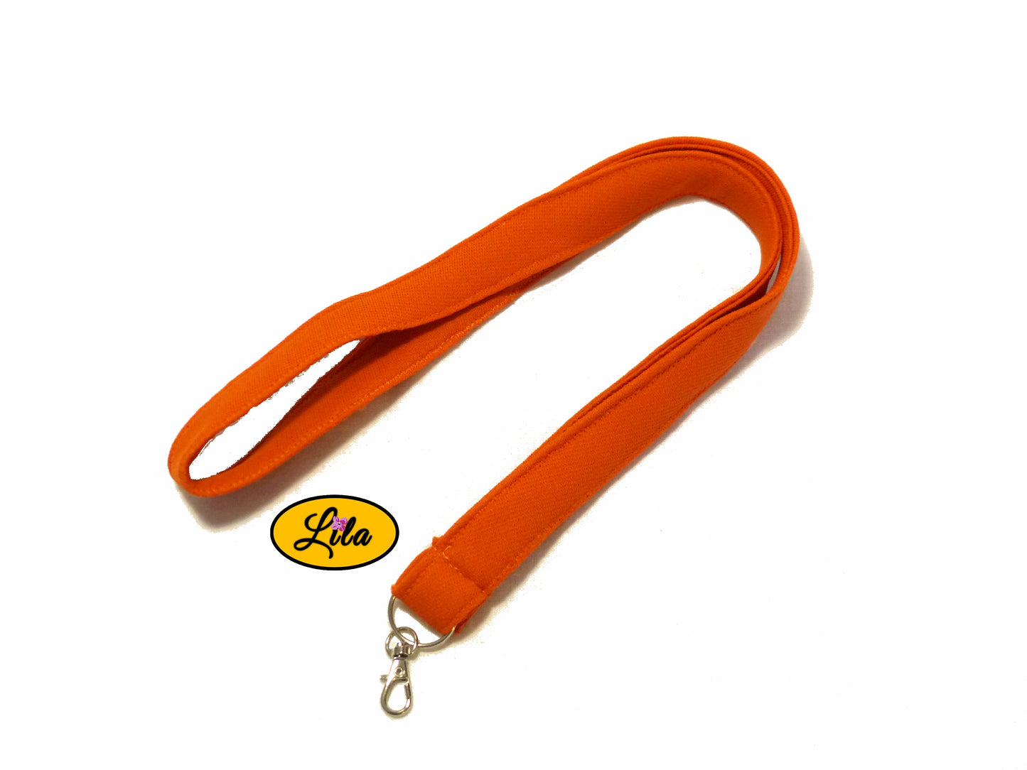 Porte-badge orange en tissu épais légèrement replié en deux sur fond blanc avec mousqueton métallique style pratique et tendance