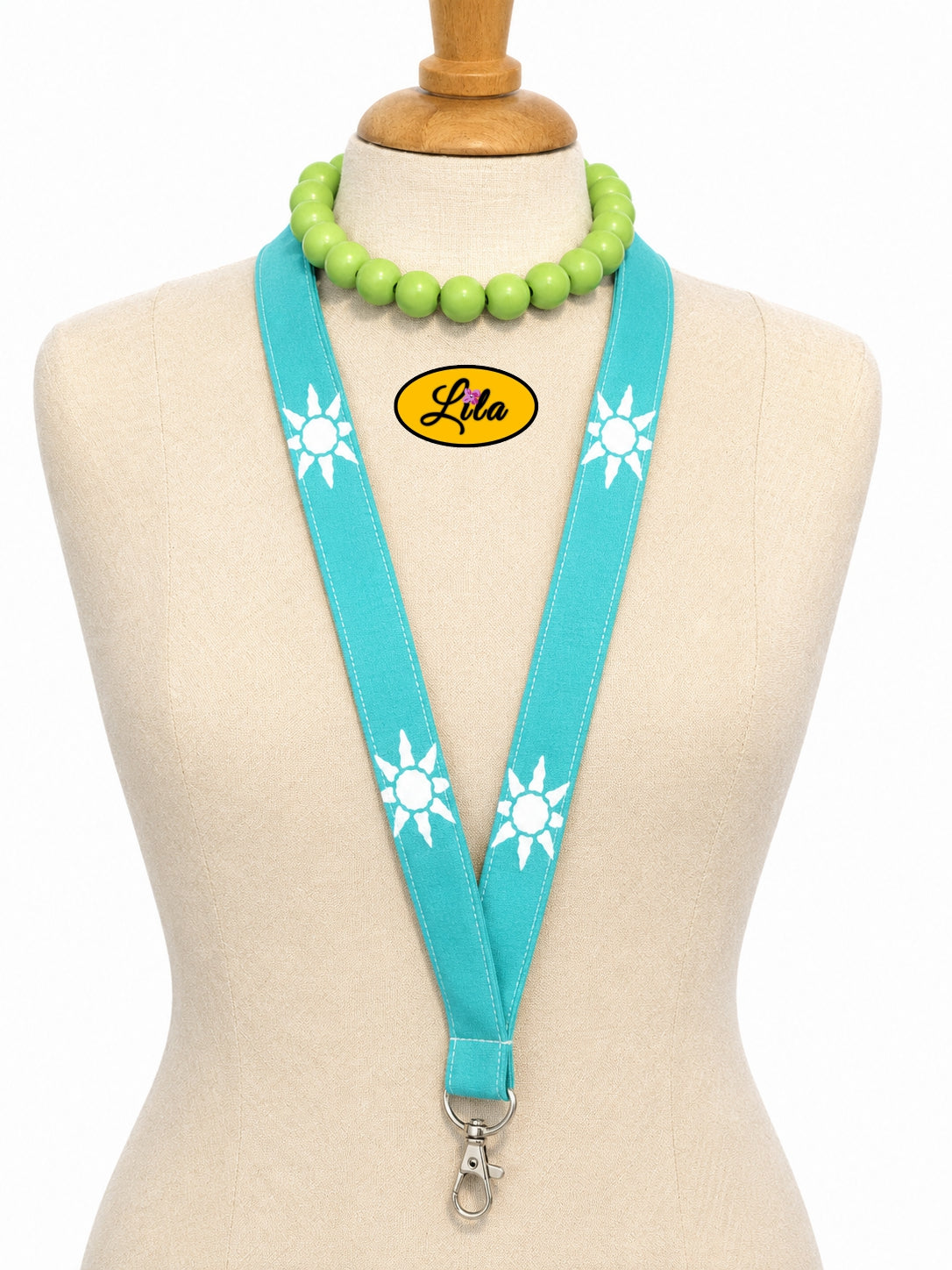 Porte-badge en tissu vert avec petits soleils blancs porté sur mannequin de couture sur fond blanc avec mousqueton style fun et artisanal