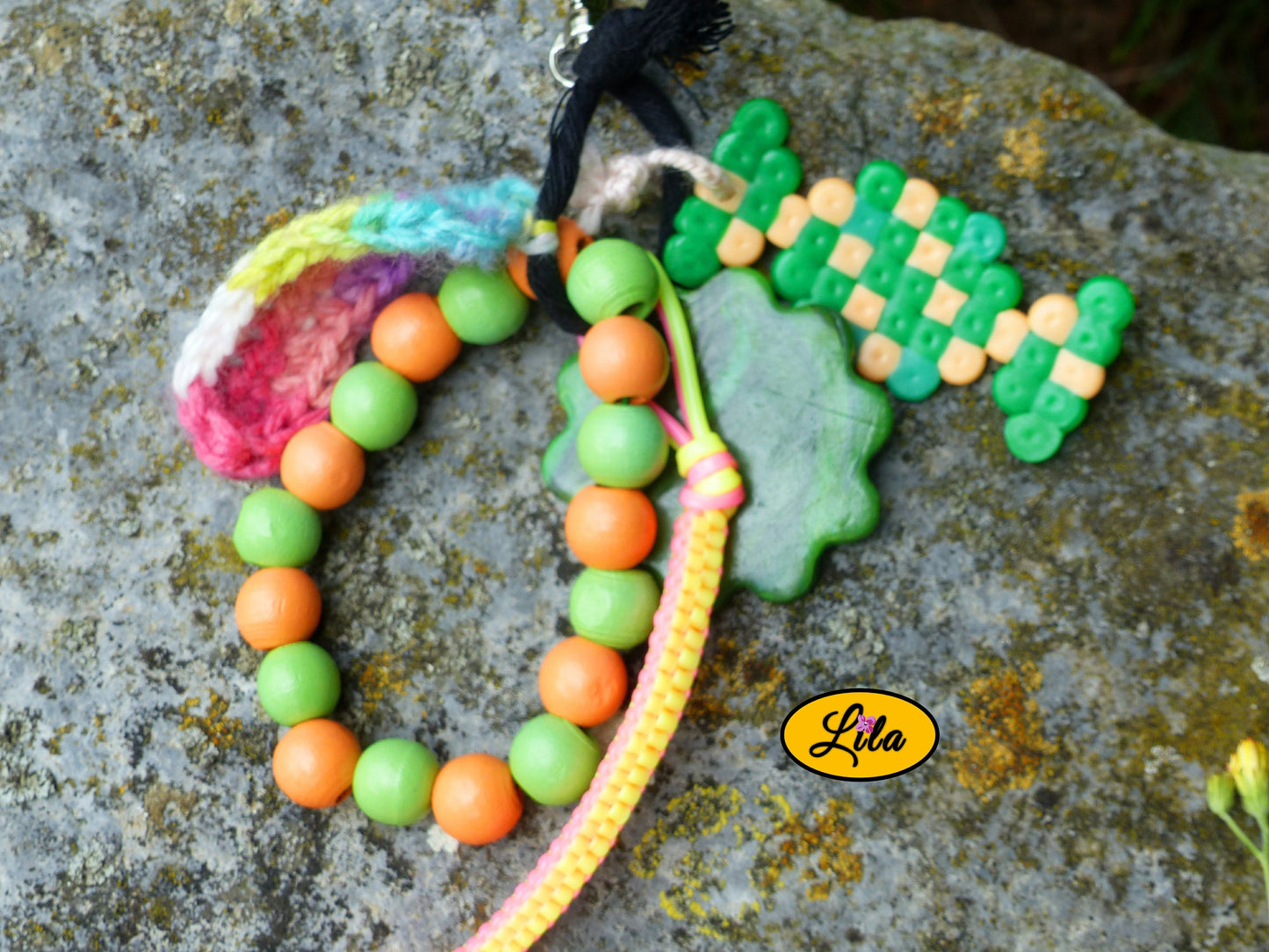 Vue rapprochée d’un porte-clés bonbon vert multicolore avec détails des perles à repasser, fleur en pâte polymère, perles en bois, scoubidou et laine crochetée style kawaii et récup créative