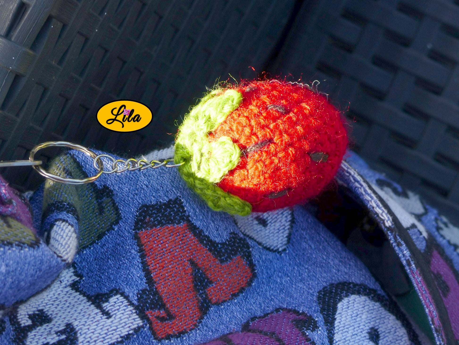 Zoom sur un porte-clé fraise amigurumi au crochet avec rayon de soleil mettant en valeur la texture de la laine style kawaii et artisanal