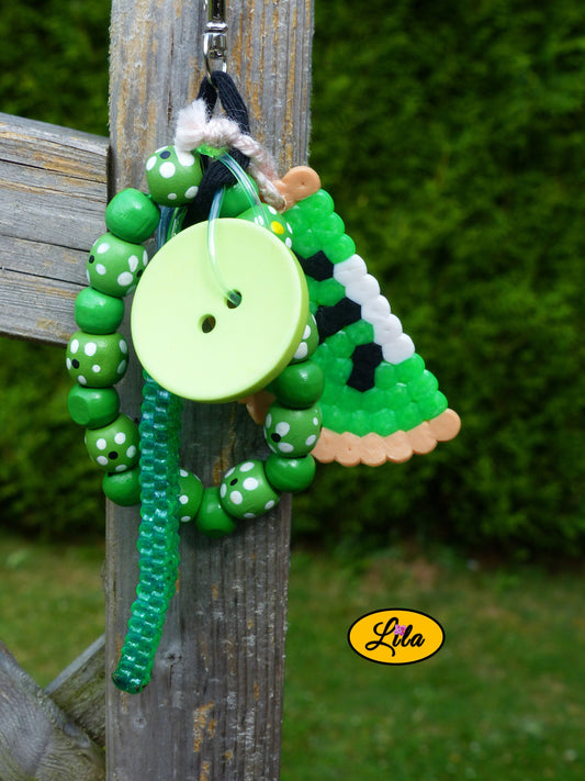 Porte-clés Kiwi vintage composé d’une demi-tranche de kiwi en perles à repasser, bracelet en grosses perles de bois vertes, scoubidou vert et bouton vert recyclé assemblés avec des bouts de laine tressée et suspendus à un mousqueton style créatif et artisanal