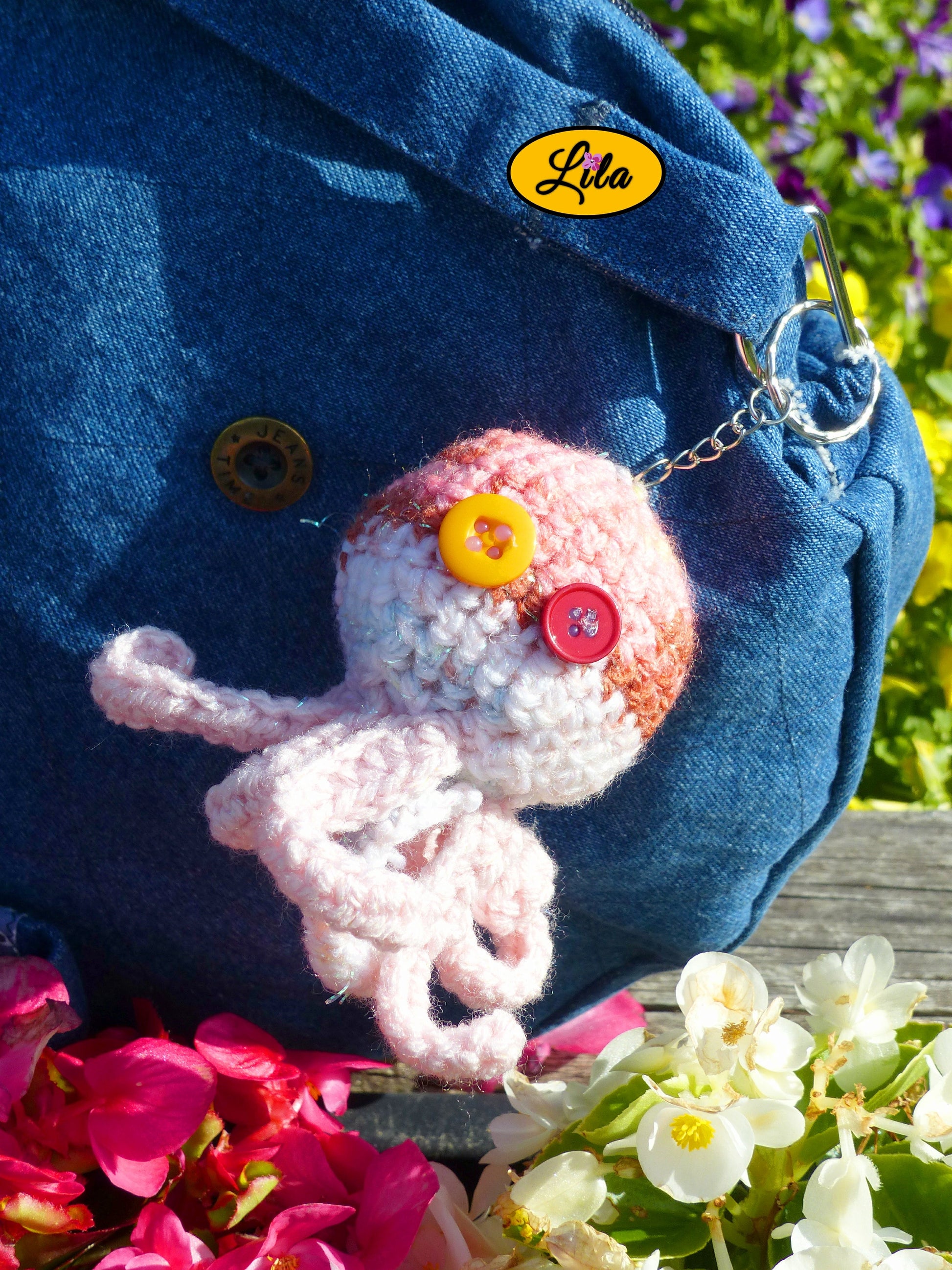 Porte-clé Poulpy pieuvre amigurumi rose aux dégradés pailletés réalisée au crochet avec yeux en boutons orange et fuchsia accroché à un sac style bohème et artisanal