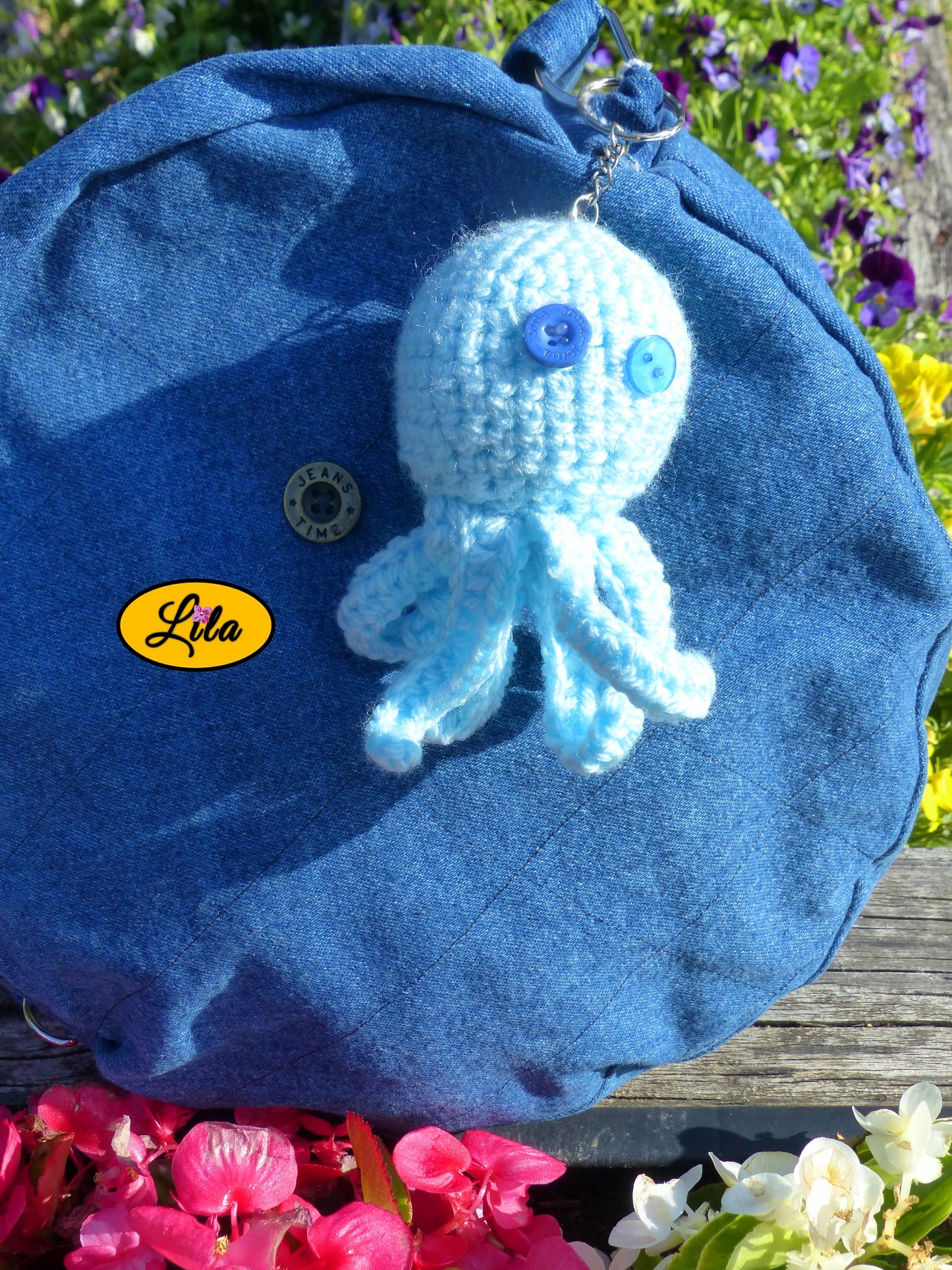 Porte-clé Poulpy pieuvre amigurumi bleu ciel réalisée au crochet avec yeux en boutons bleus de différentes épaisseurs accroché à un sac style bohème et artisanal