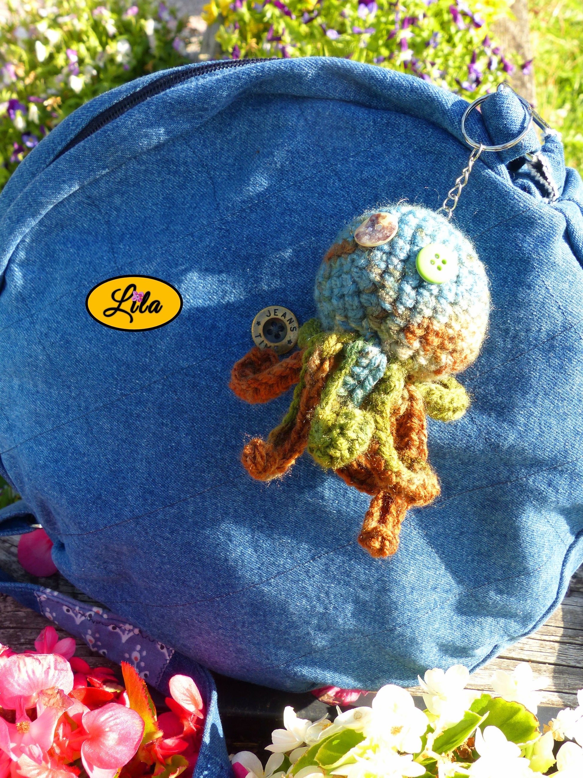 Porte-clé Poulpy pieuvre amigurumi chamarrée aux tons vert bleu et brun réalisée au crochet avec yeux en boutons vert et multicolore accroché à un sac style bohème et artisanal