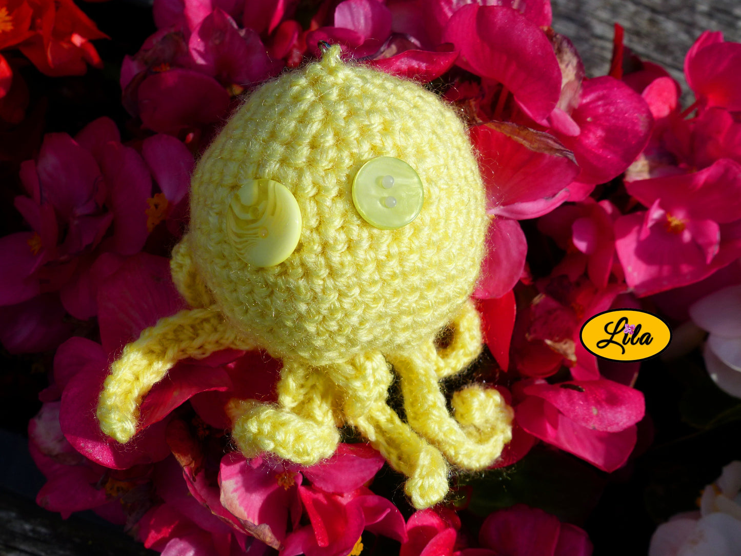Porte-clé Poulpy pieuvre amigurumi jaune réalisée au crochet avec yeux en boutons jaunes de différentes teintes posé sur un lit de fleurs style kawaii et artisanal