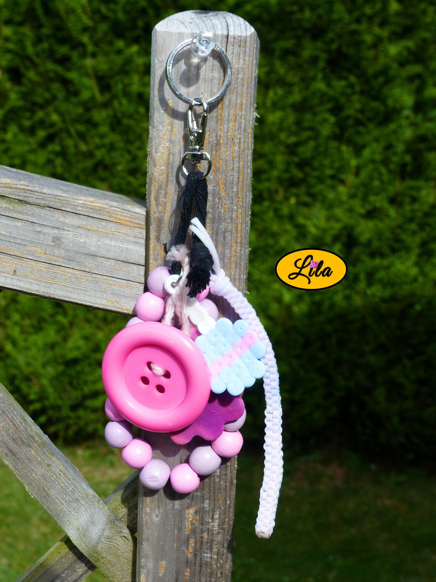 Porte-clés rose sucrée rétro chic composé d’une sucette pastel en perles à repasser, fleur en pâte polymère rose dégradé, bracelet en grosses perles mauves et roses pastel, scoubidou pastel, gros bouton rose et bouts de laine tressée suspendus à un mousqueton style kawaii et artisanal