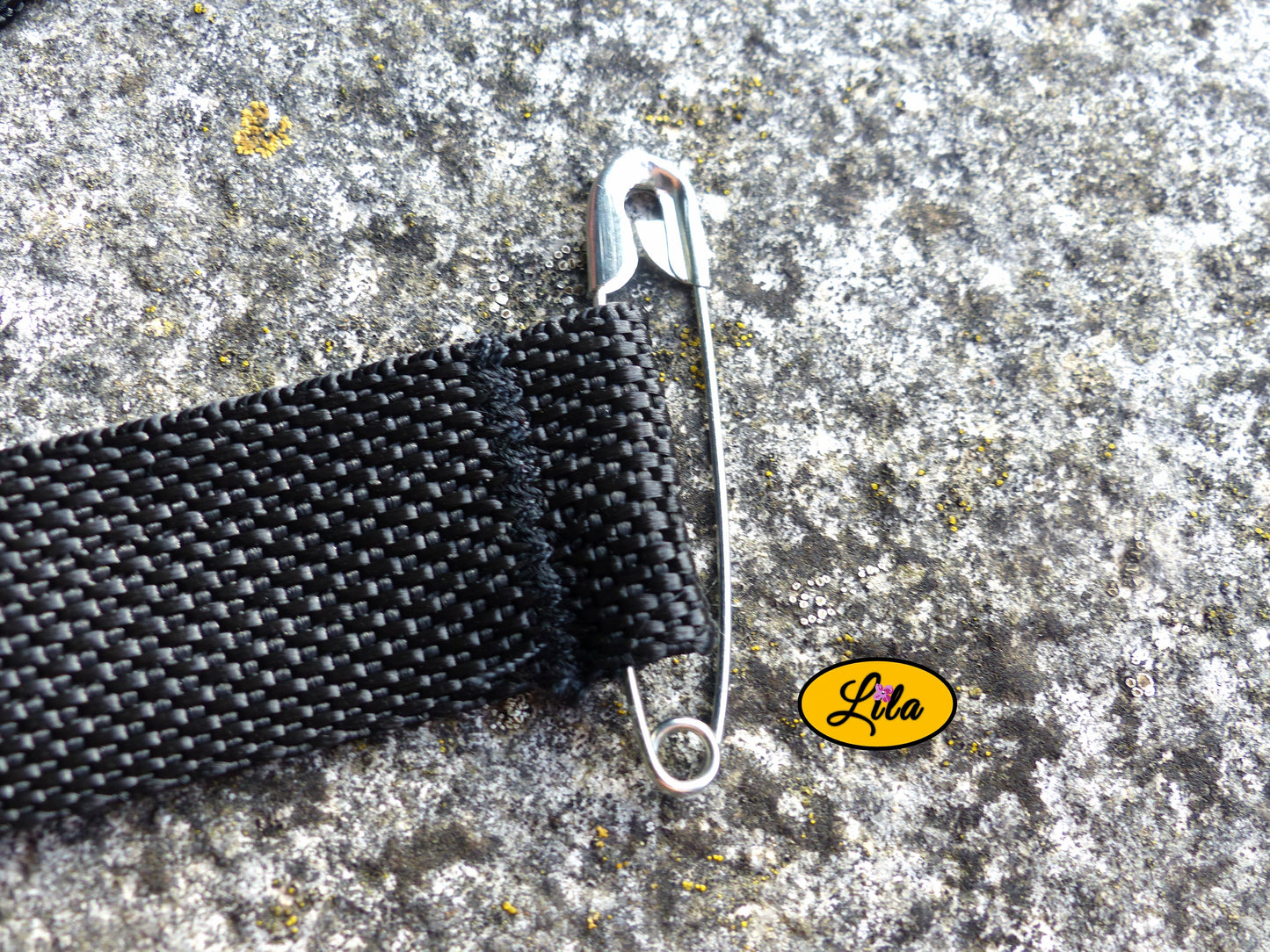 Zoom sur l’épingle de fixation d’un porte-gobelet crocheté rose avec ceinture noire style artisanal et pratique