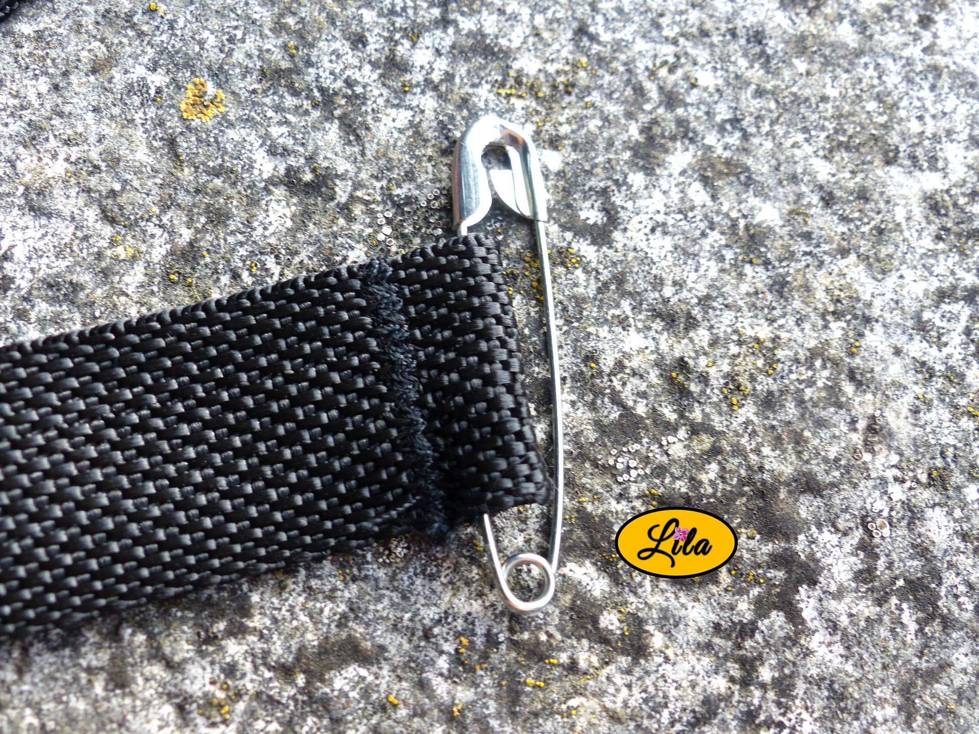 Zoom sur l’épingle de fixation d’un porte-gobelet crocheté rose avec ceinture noire style artisanal et pratique